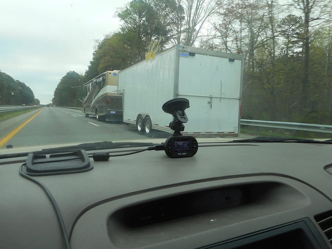 A pickup towing an enclosed trailer on a highway, seen from a following vehicle