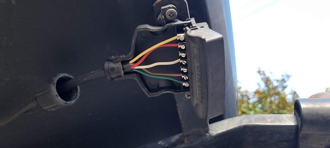 A 7-pin trailer socket opened up with its individual wires connected to the terminals